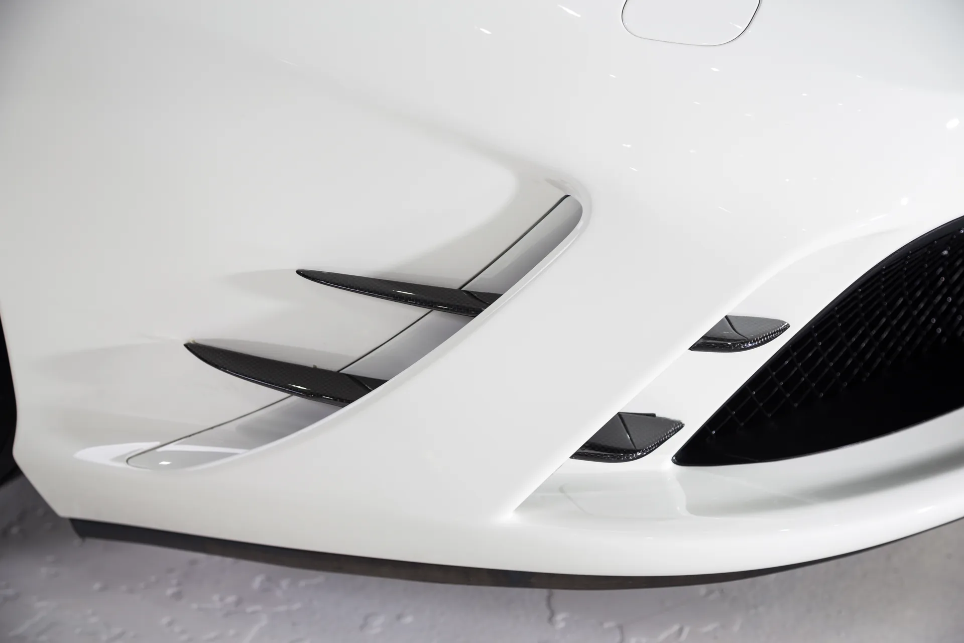 Ein Hypercar mit tiefgezogener Karosserie steht im dramatisch ausgeleuchteten Showroom