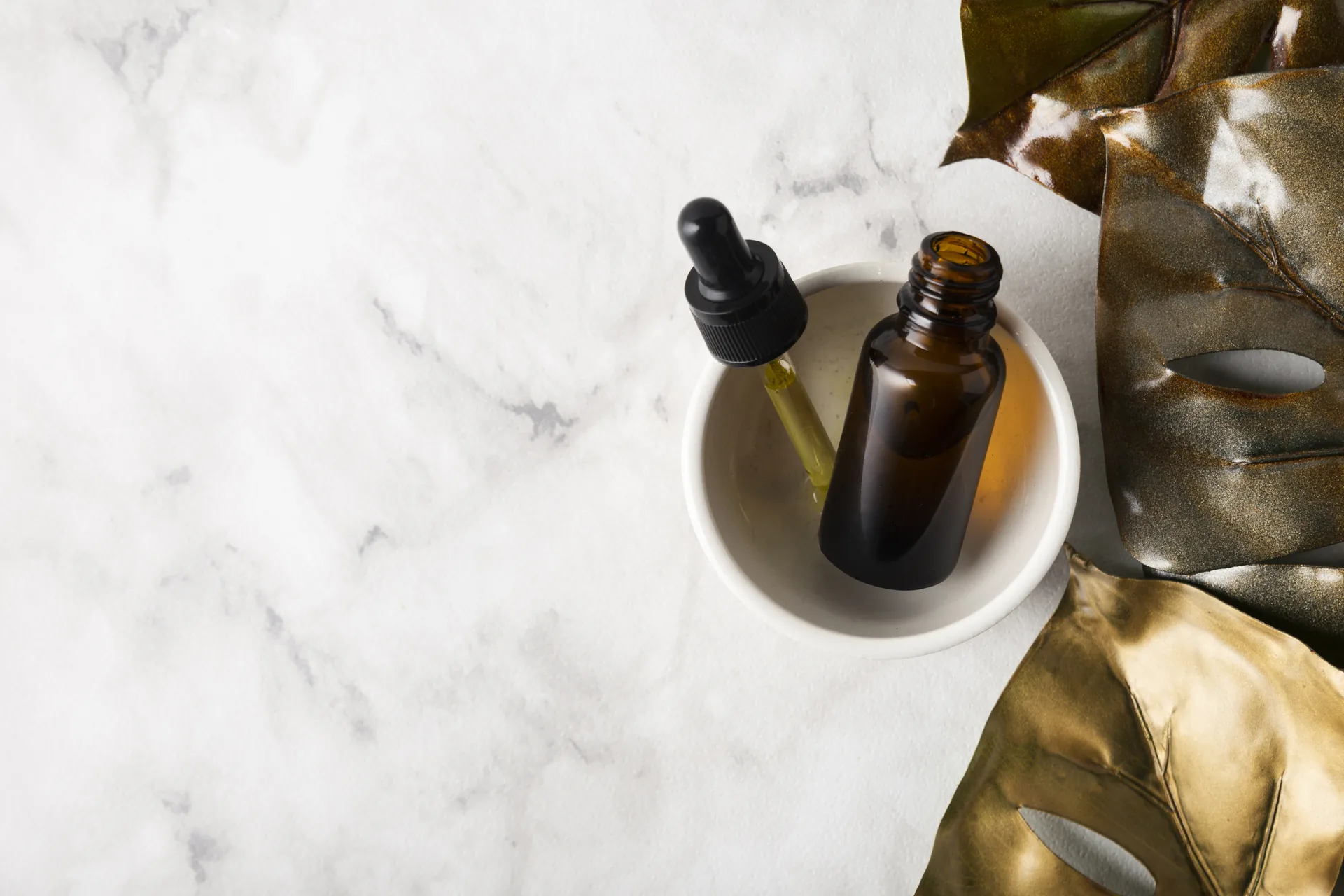 Elegant arrangiertes Luxus-Hautpflege-Serum in einer Glasflasche auf hellem Marmor im weichen Tageslicht