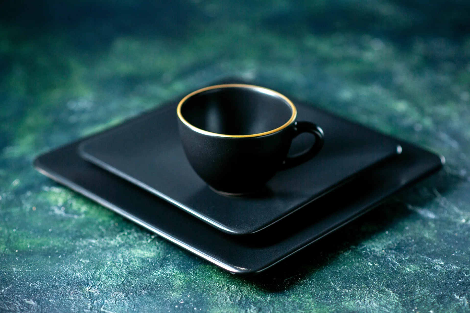 Elegante Espressotasse aus feinem Porzellan mit dunklem Kaffee, umgeben von gerösteten Bohnen auf edlem, dunklem Untergrund