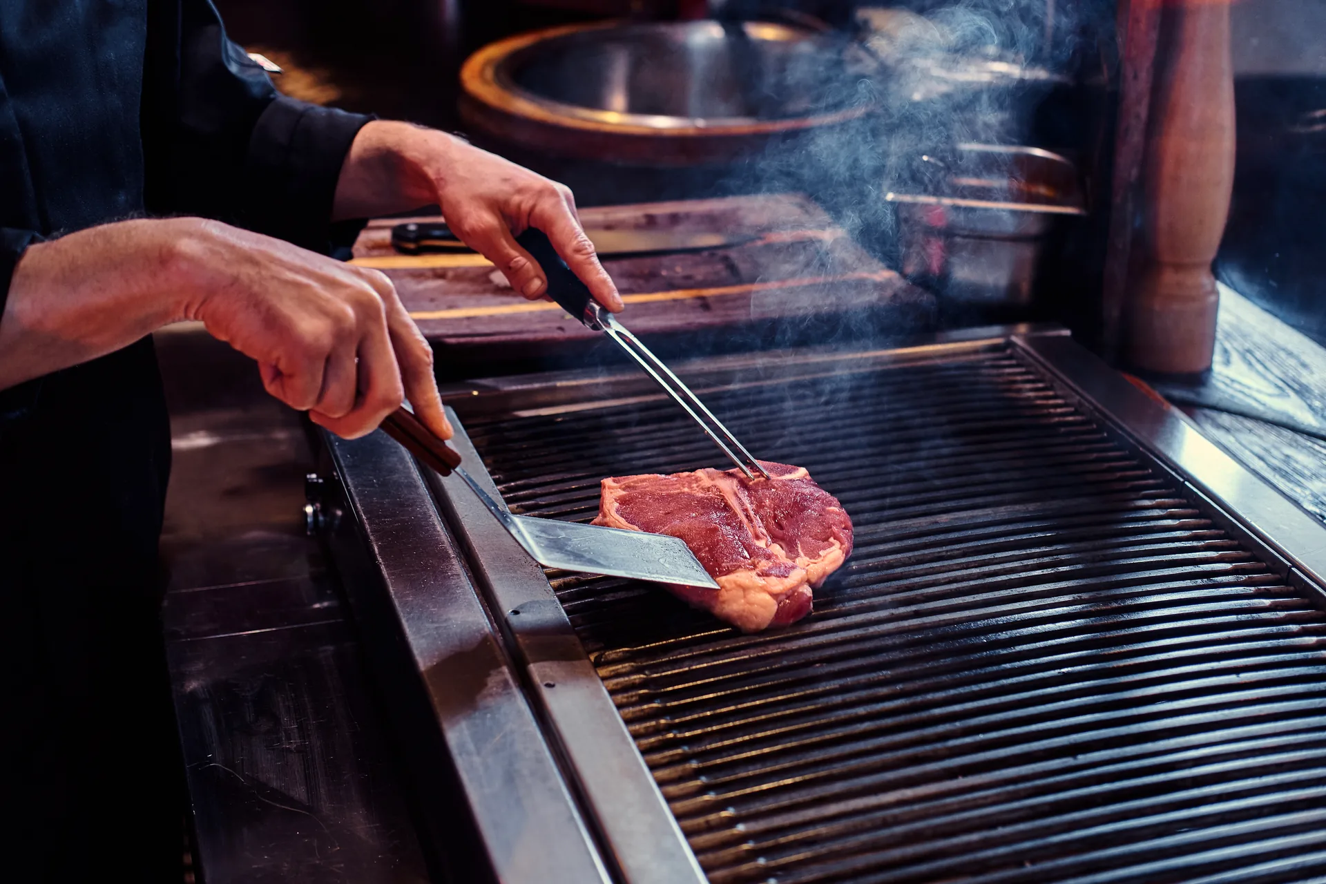Teppanyaki-Koch bereitet Wagyu-Rind auf der heißen Eisenplatte vor Gästen zu