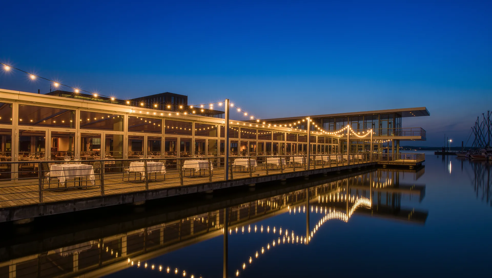 Gedeckte Restaurantterrasse am Wasser im Düsseldorfer Medienhafen zur blauen Stunde