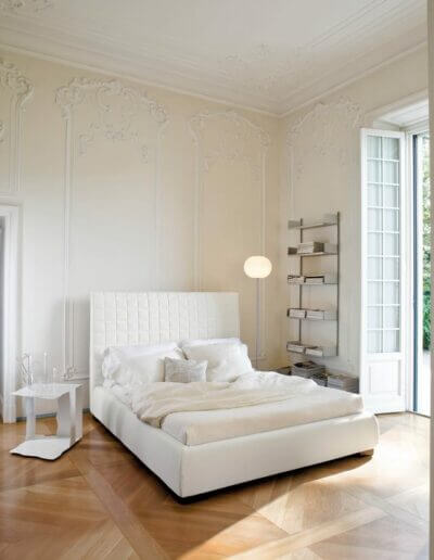 Ein weißes Schlafzimmer mit Holzböden und einem weißen Bett.