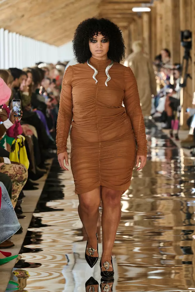 Ein Model läuft in einem braunen Kleid über den Laufsteg.